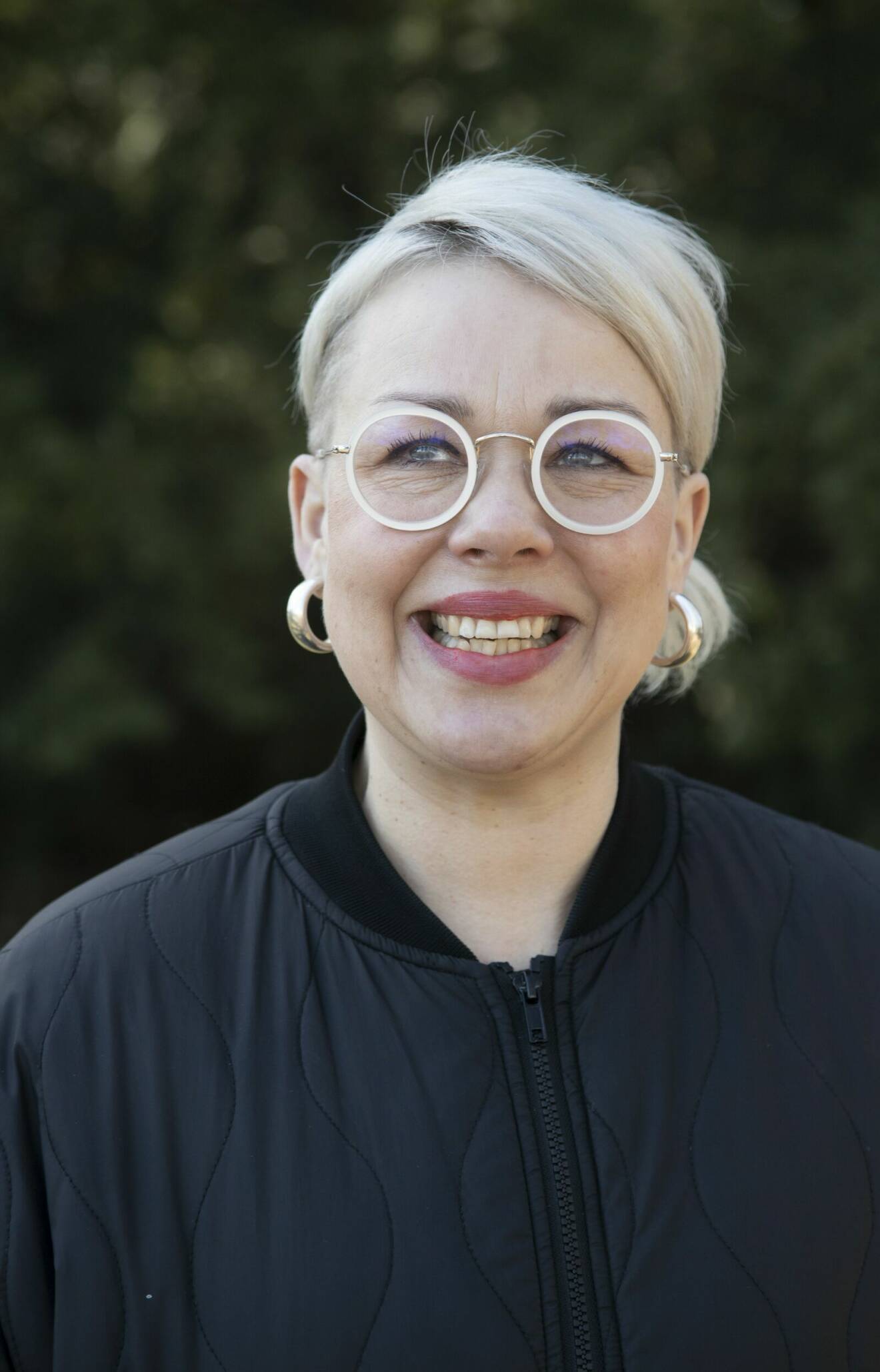 Nettan Johansson ler med suddig grönska i bakgrunden.