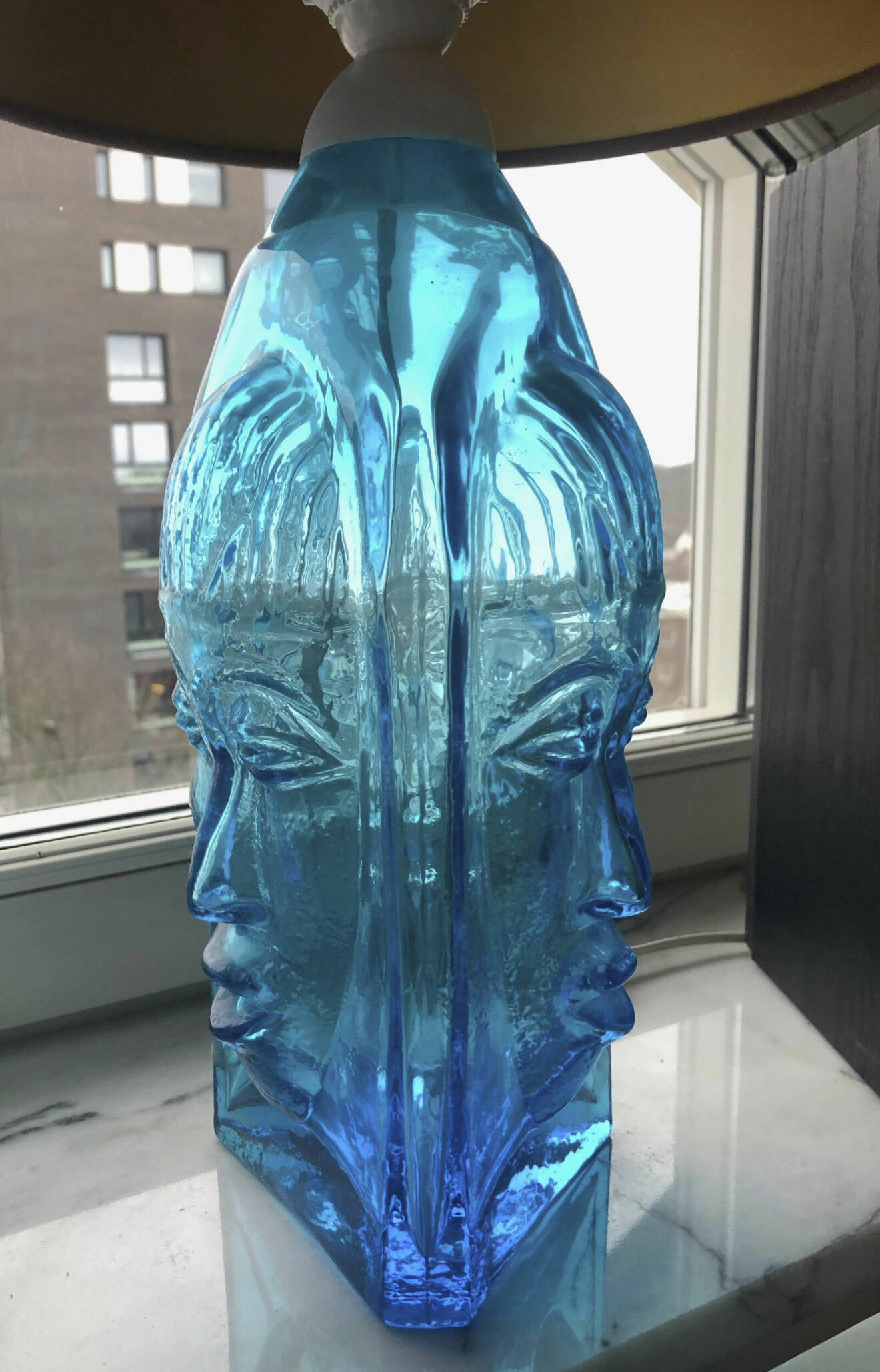 Lampa i blått glas med två kvinnoansikten på foten.