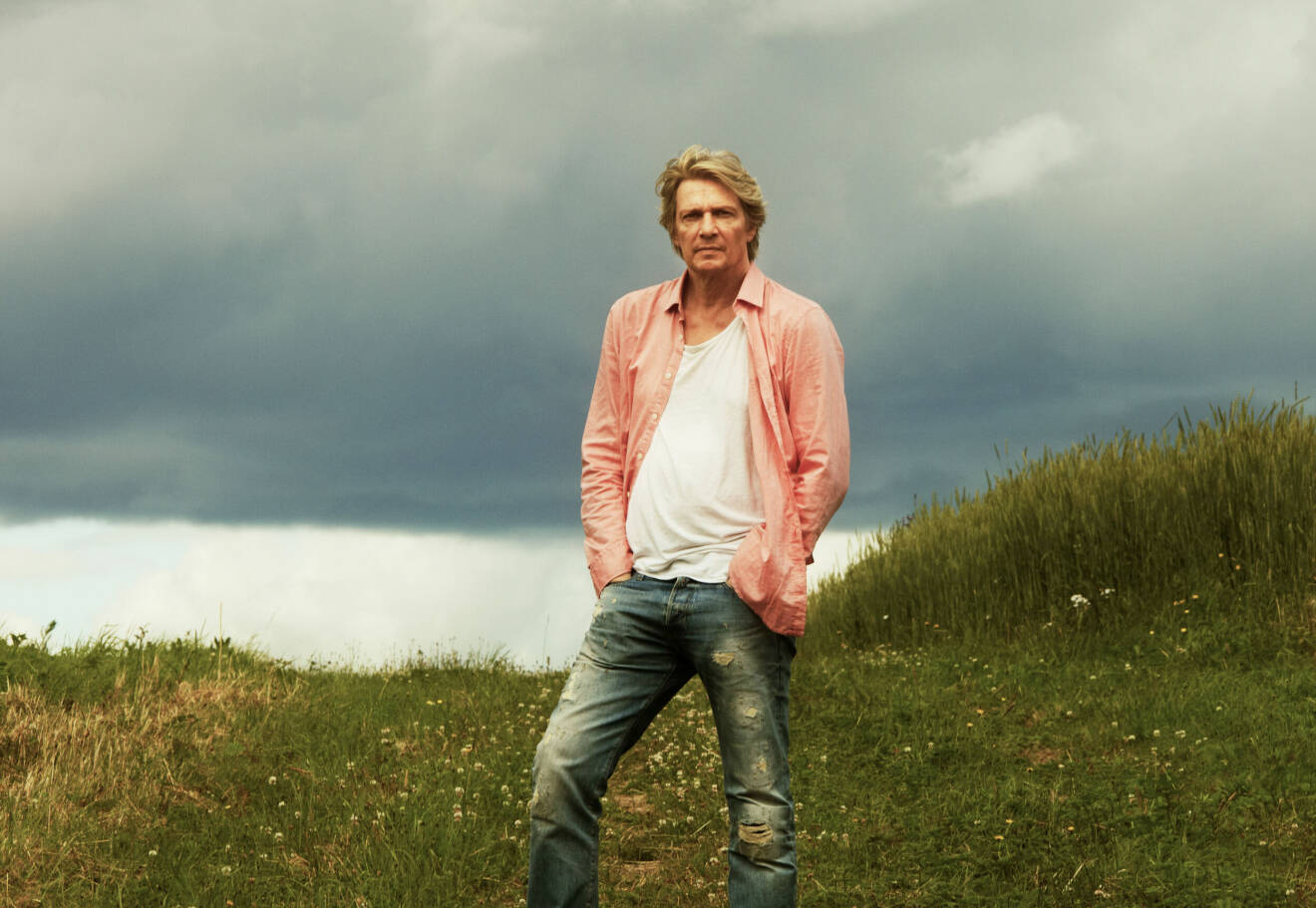 Tommy Nilsson upplever naturen, iklädd slitna jeans, vit t-shirt och rosa skjorta.