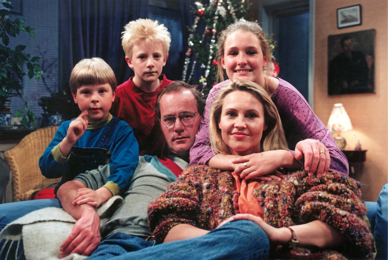 Bild på skådespelarna i julkalendern Sunes Jul. De sitter i ett vardagsrum med en julgran i bakgrunden.