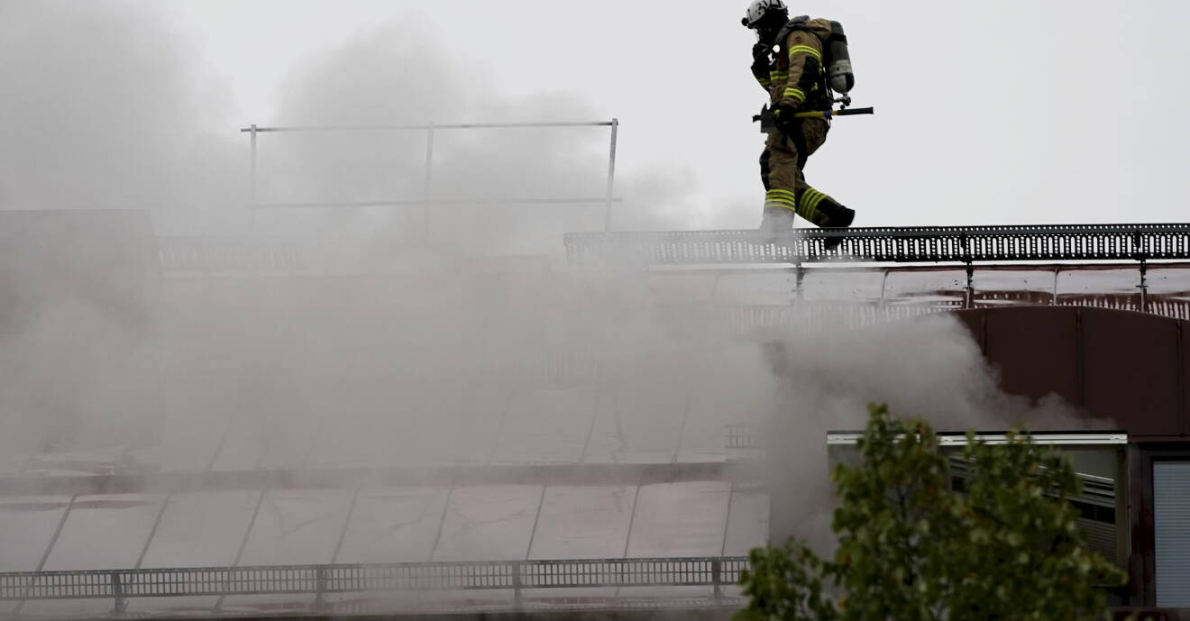 Brandman på stege på taket ovan kraftig rökutveckling.