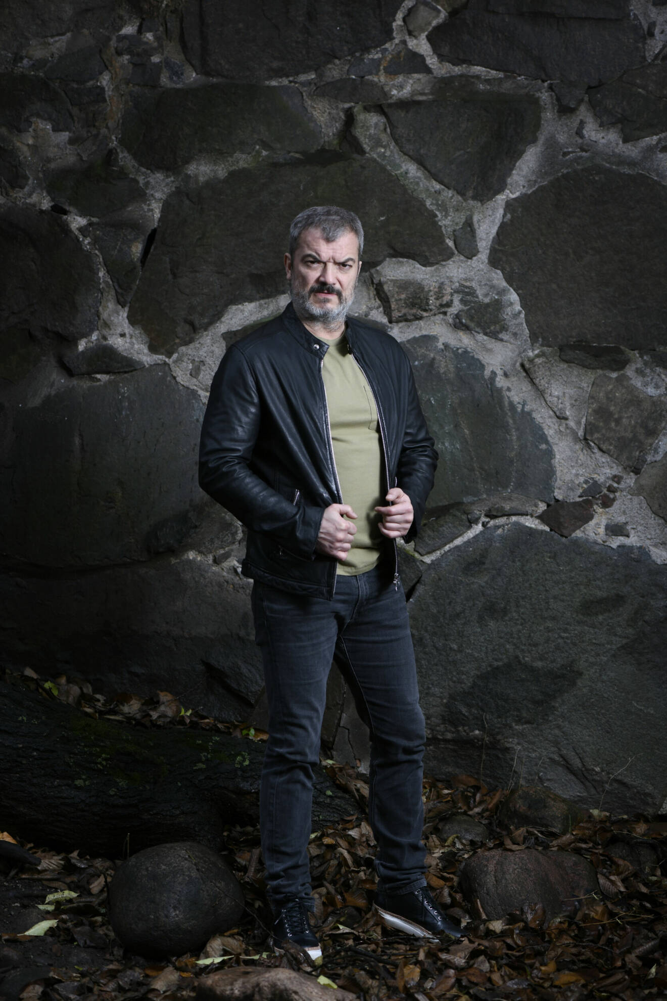 Dragomir Mrsic, skådespelare med kriminellt förflutet, i mörka kläder och med en svart-grå rå vägg som bakgrund.