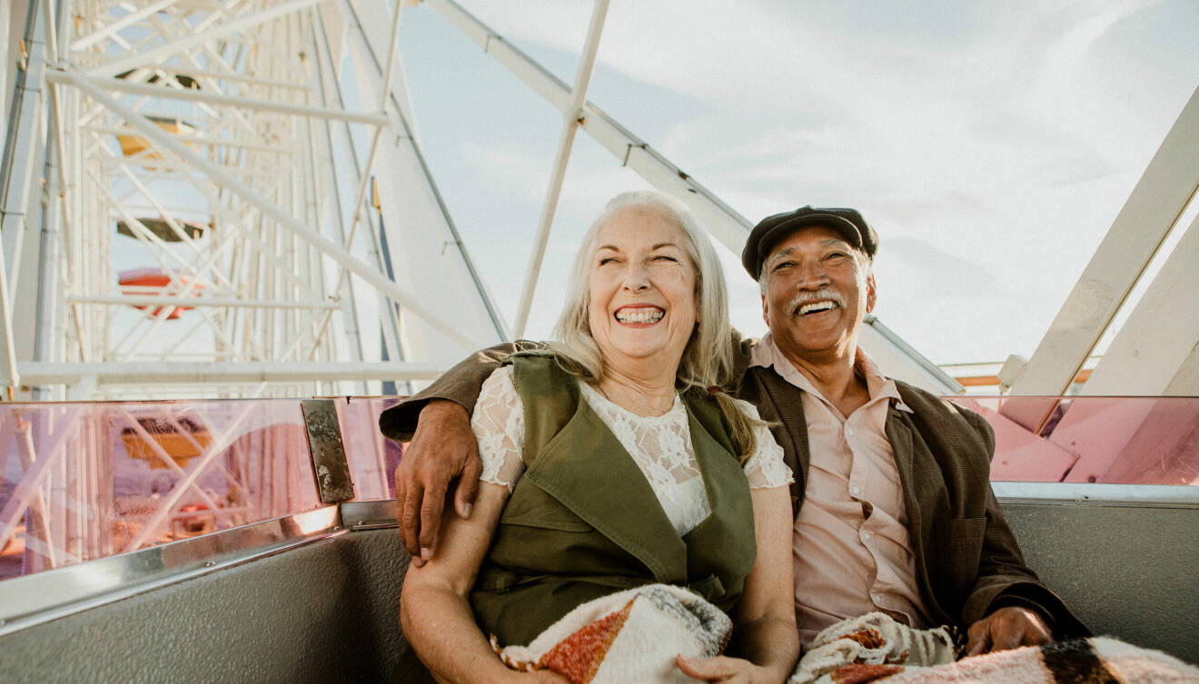 En äldre man och kvinna skrattar när de åker i ett pariserhjul