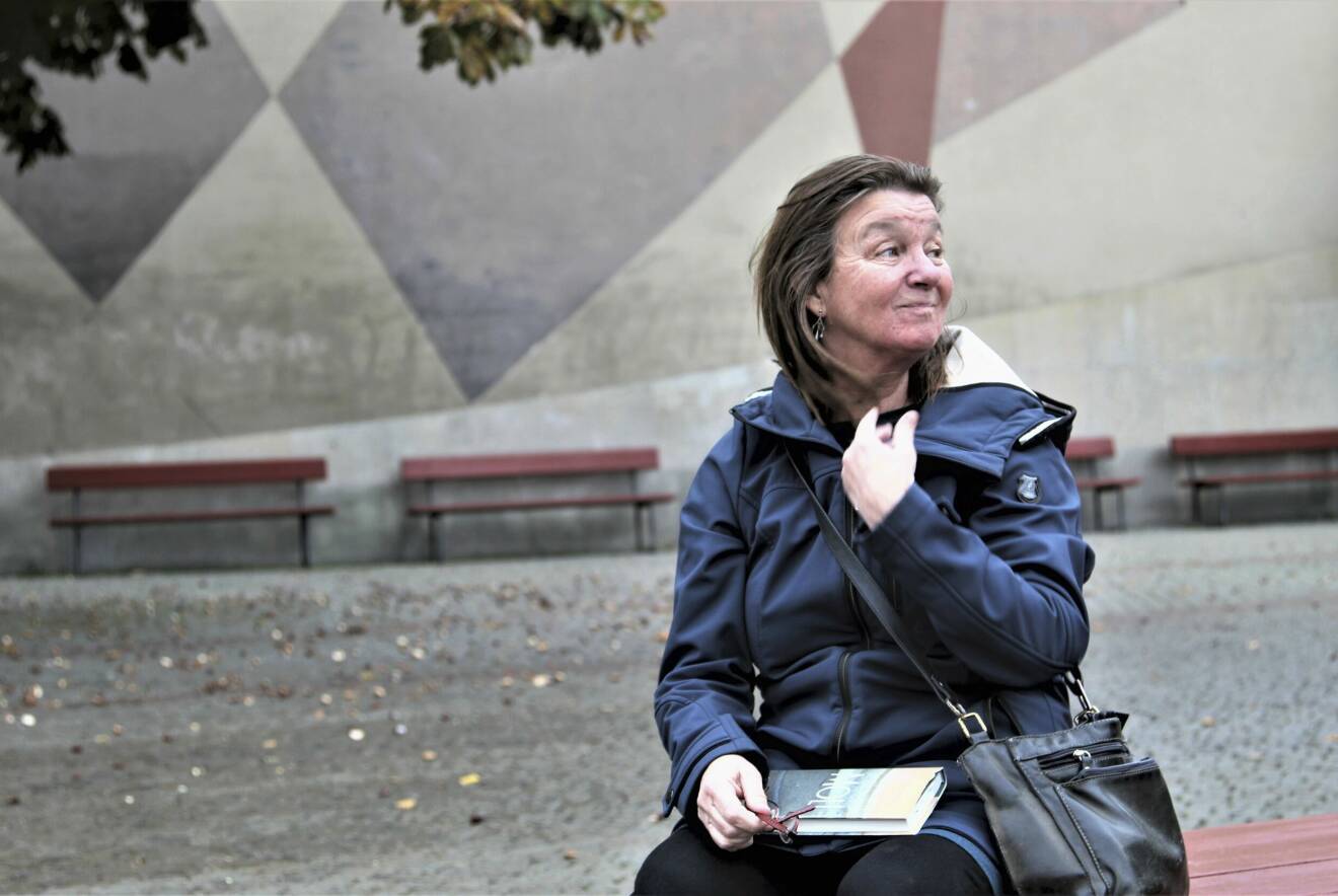 Elisabeth Rynell sitter på en bänk utomhus, med sin senaste bok Moll i knät.