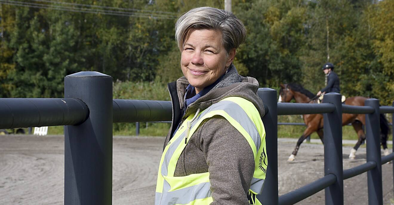 Läkaren Maria Furberg är ansvarig läkare vid distriksmästerskapen i Umeå och står som standby vid en av hästbanorna och i bakgrunden syns en ryttare på en häst.