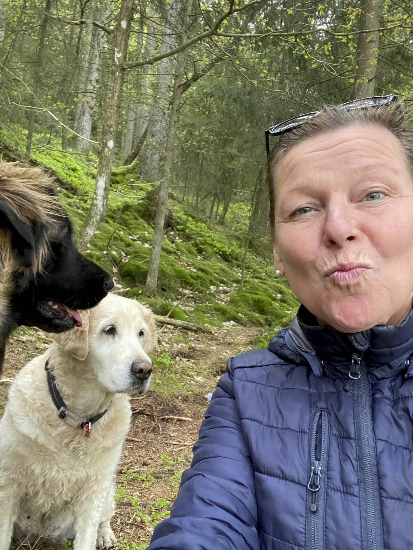 Lotta Engberg, vid sidan om sina två hundar i skogen, gör en puss i luften.