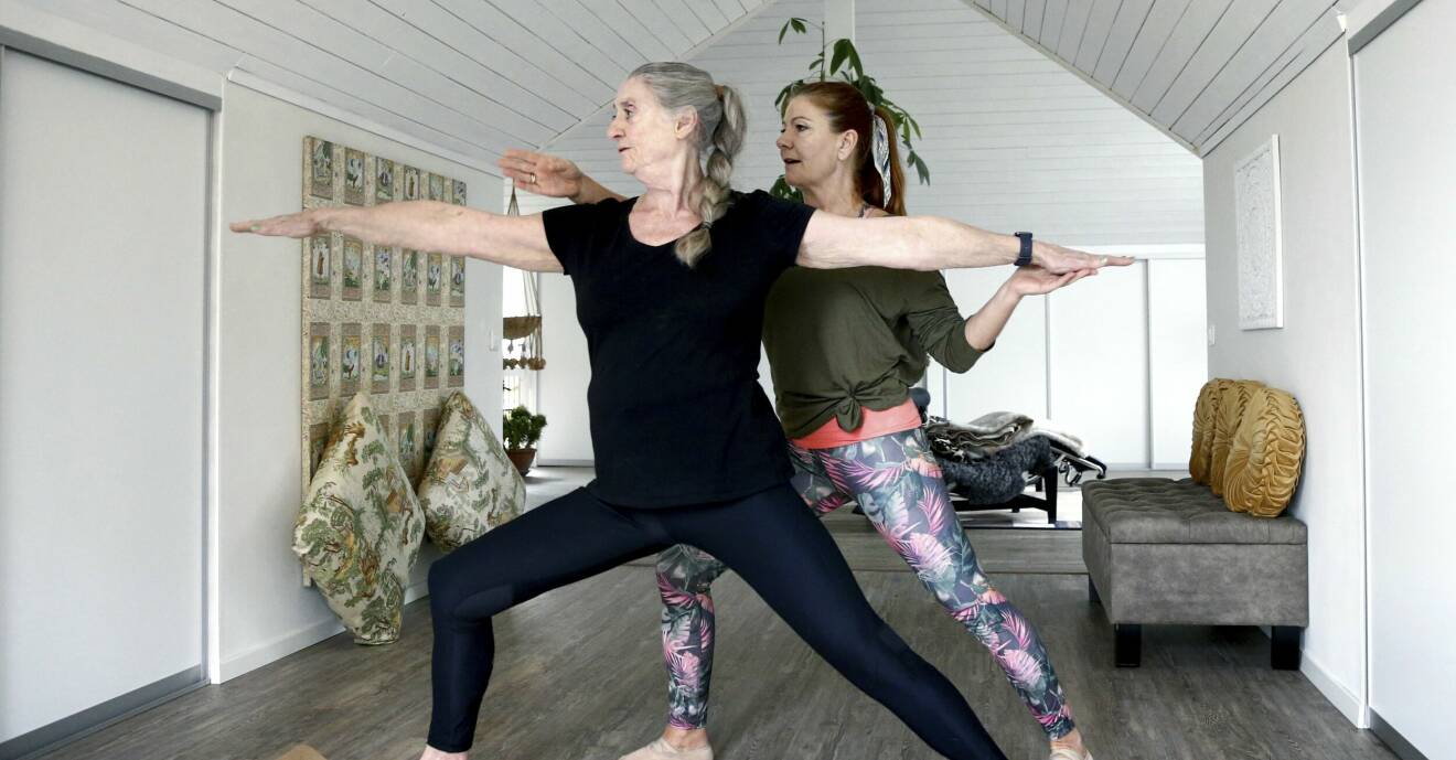 Yogaläraren Susanne Lovensjo står bakom Solveig och instruerar henne i yoga.