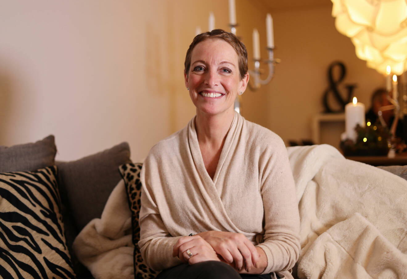 Jenny Kroon sitter i soffan hemma hos sin syster och berättar om den hjärntumör som upptäcktes 2020.