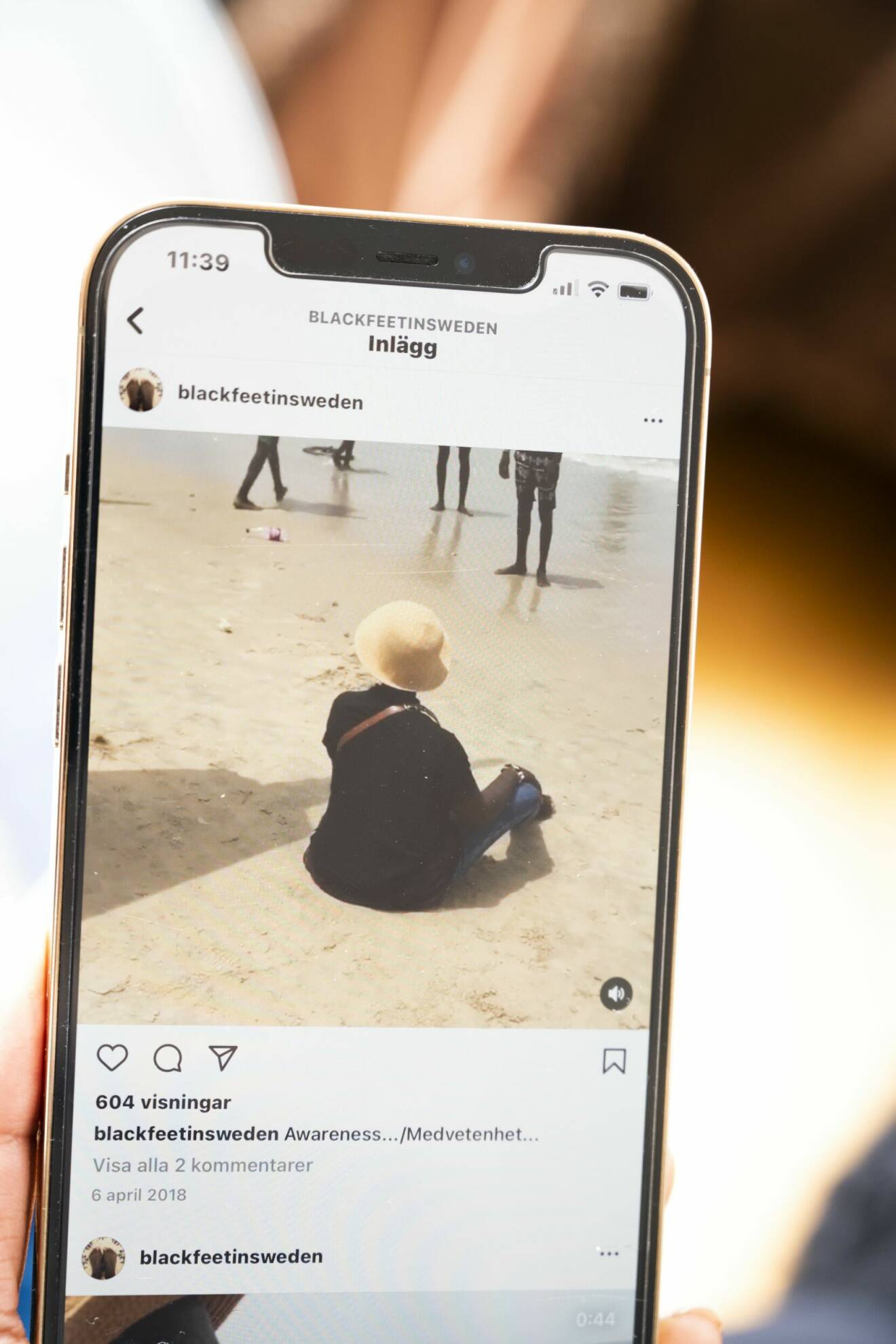 Madeleine visar ett Instagram-inlägg på mobilen, en bild där hon sitter på en strand i Senegal, med ryggen mot kameran.