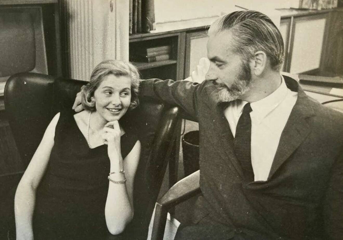 Birgitta och Piers sitter på varsin stol bredvid varandra, tittar varandra i ögonen och ler, på en gammal svart-vit bild.