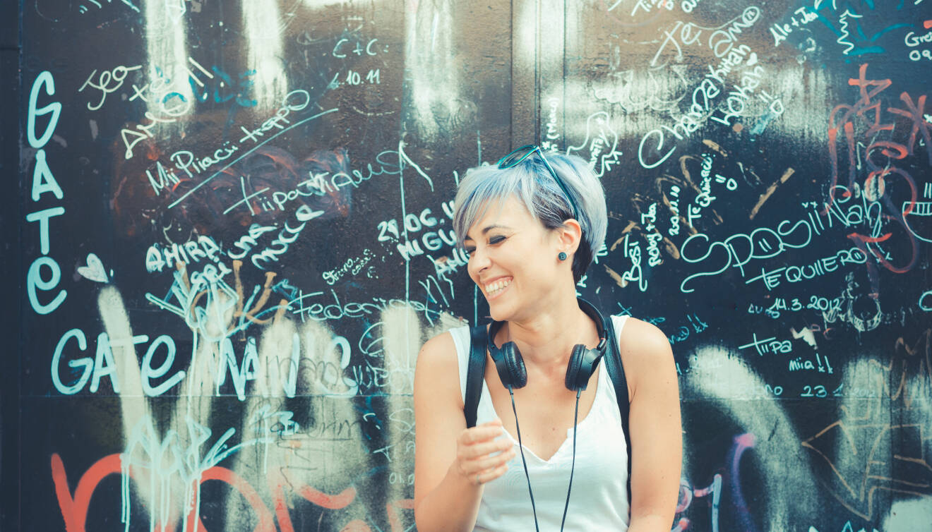 En glad kvinna mot en vägg full av grafitti