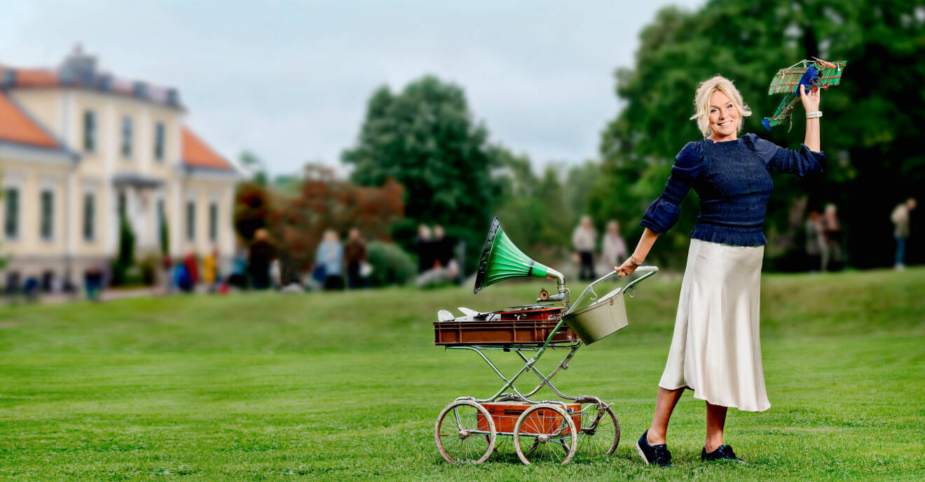 Anne Lundberg med en gammal barnvagn och andra antikviteter på en pressbild för Antikrundan 2022.