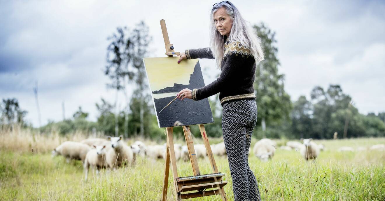 Lene Søe Rasmussen står vid sitt staffli framför en äng med får och berättar om hur det var när hon sålde de mesta av sina ägodelar, sa upp lägenheten och flyttade i sin en husvagn.
