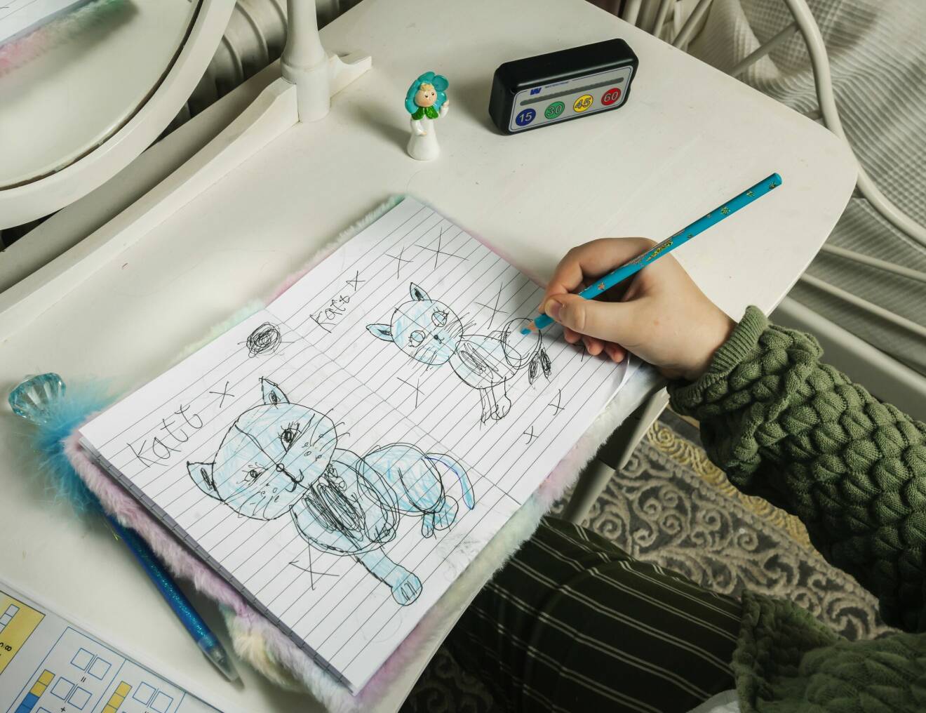 Emma Broström Andersson ritar katter i en skrivbok.