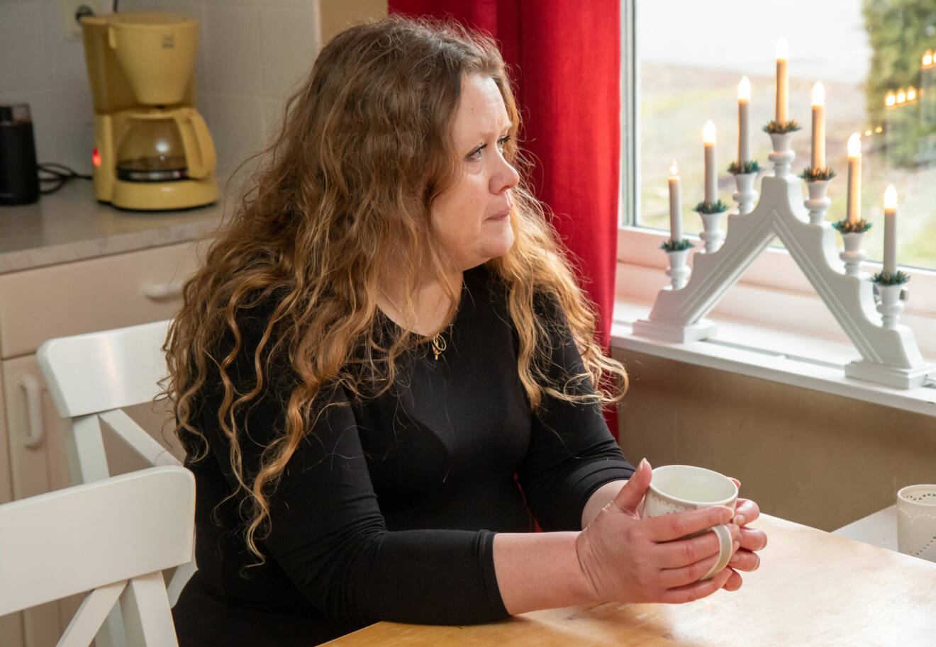 Ulrika Hägerstrand sitter vid sitt matbord i köket hemma i Hasslö, Karlskrona, med en kaffekopp.