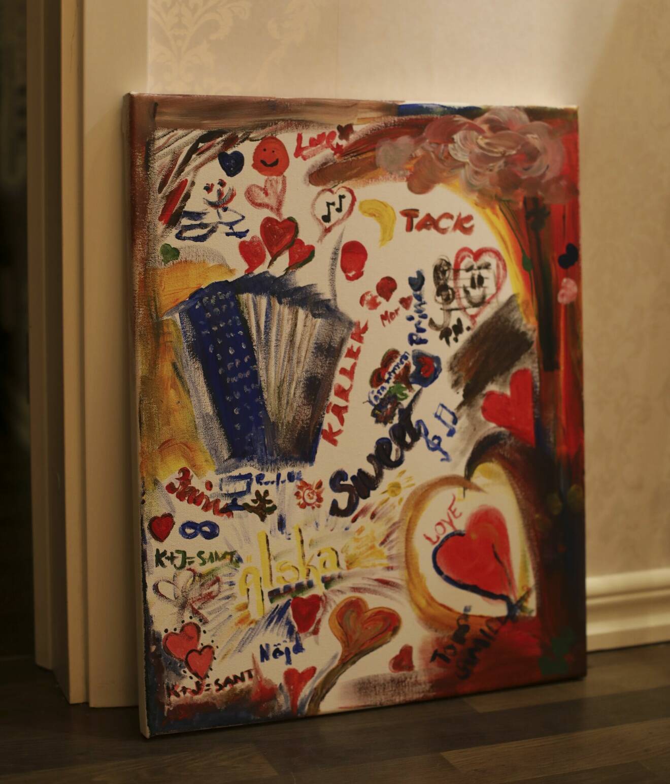 En stor och färgglad tavla med många hjärtan, målad av flera händer.