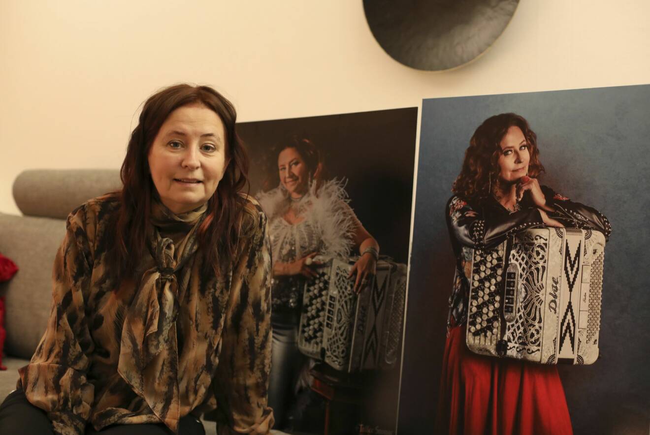 Karina Storm framför stora affischer/tavlor på sig själv med dragspelet.