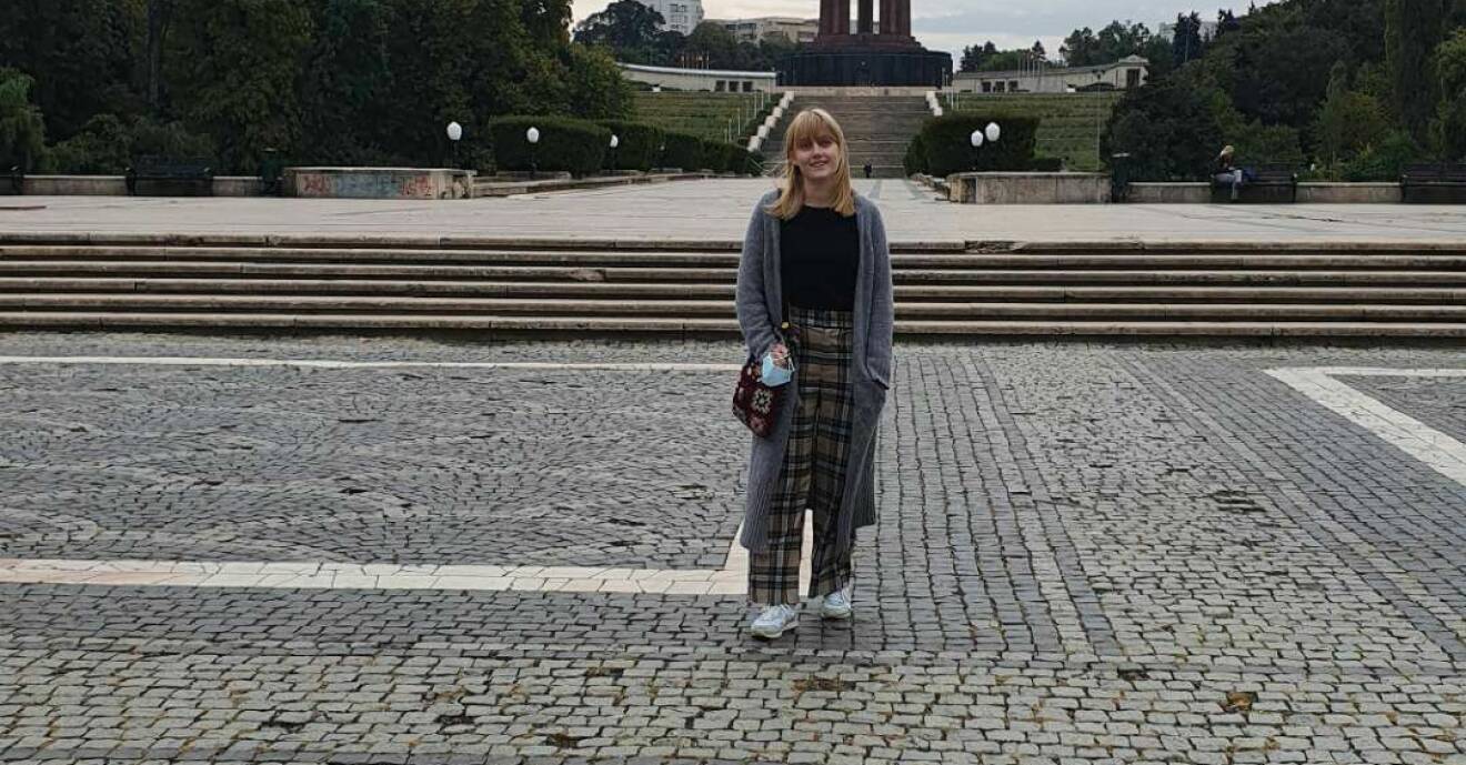 Fredrika Menninga framför ett monument i Rumänien, dit hon reste under 2021 för att utredas för endometrios.