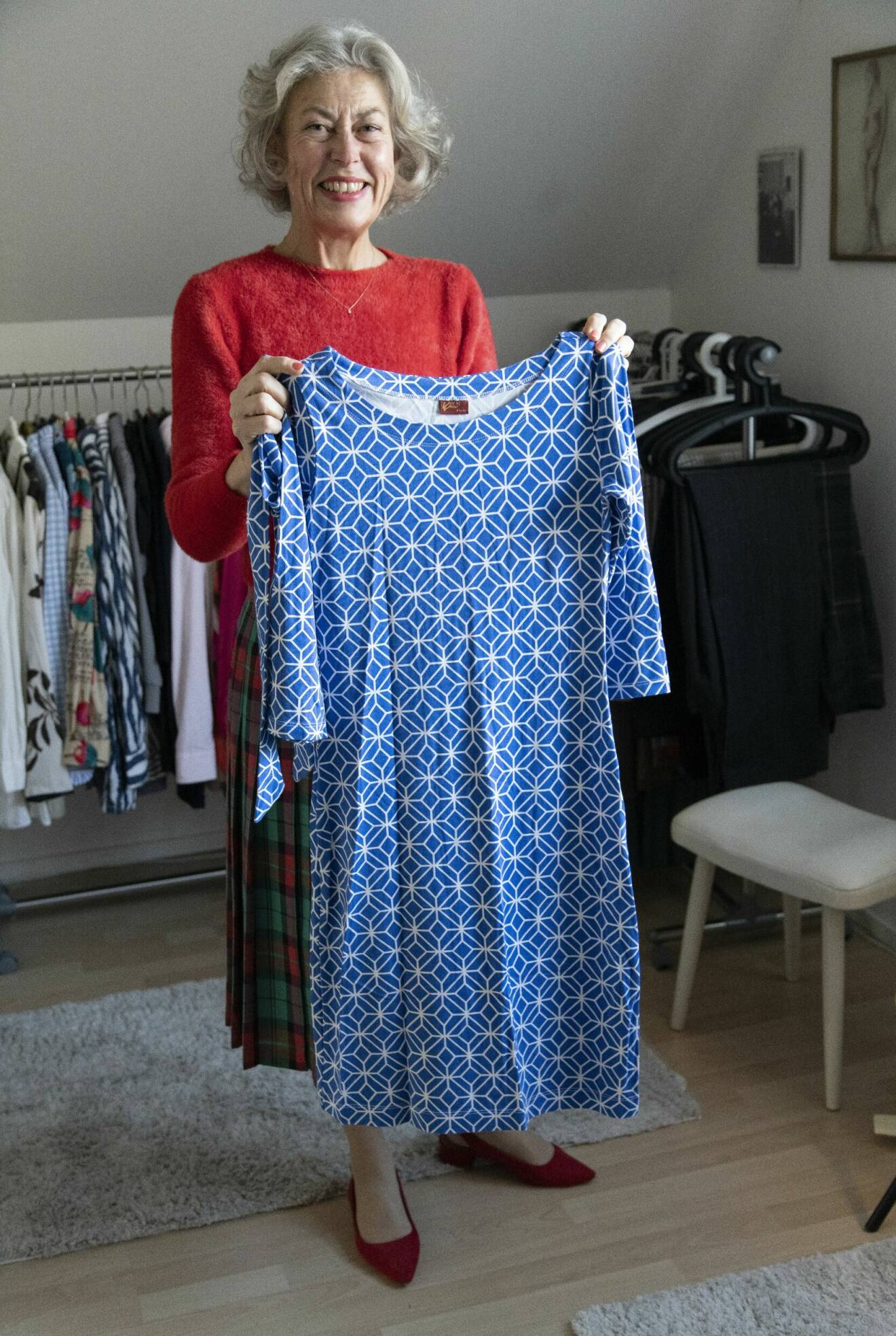 Maria Sörensson håller upp en blå vårklänning med geometriskt mönster.