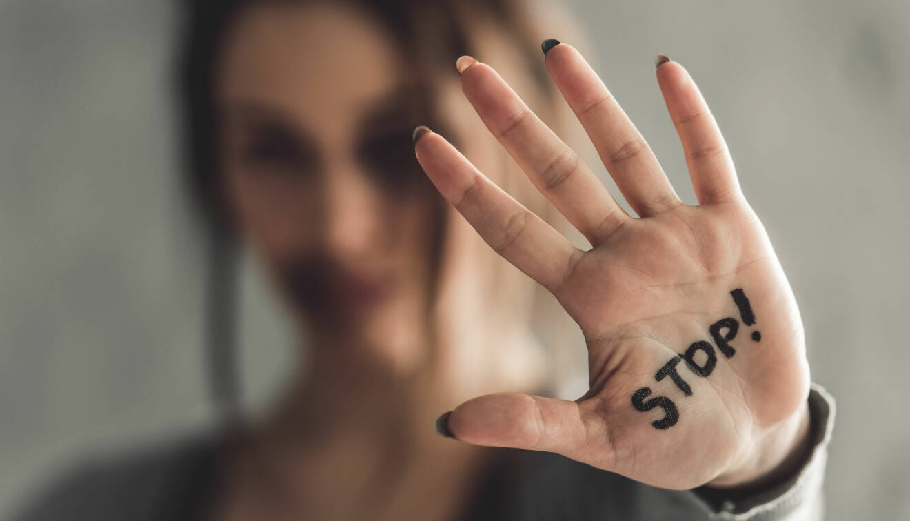 En kvinna håller upp handflatan och i den står ordet "Stop!"