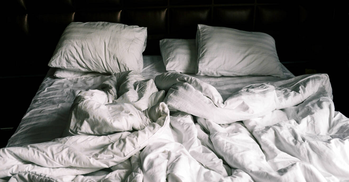 En obäddad säng med vita sängkläder.