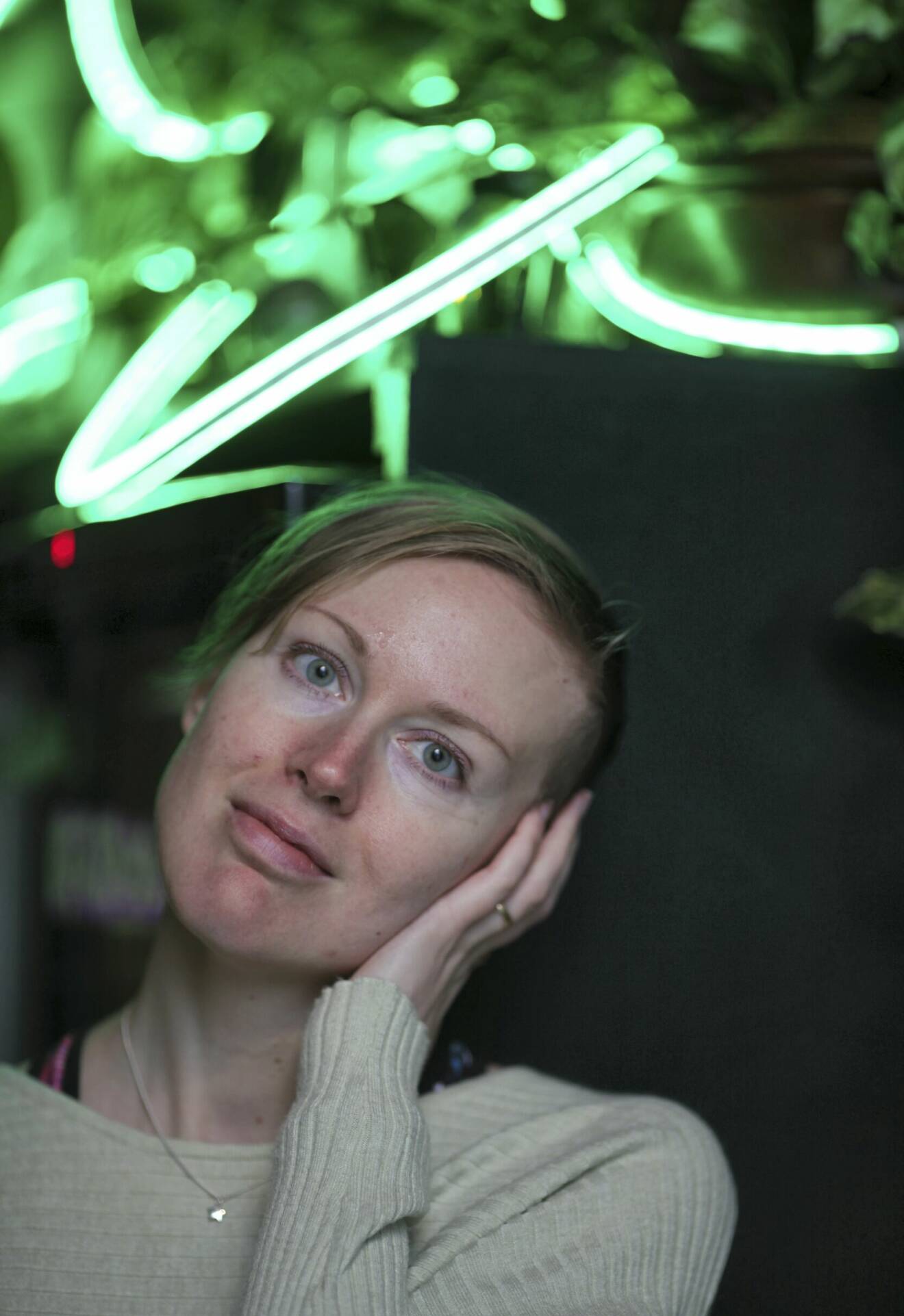 En leende Erika Lindquist med lysrör i neon i bakgrunden.