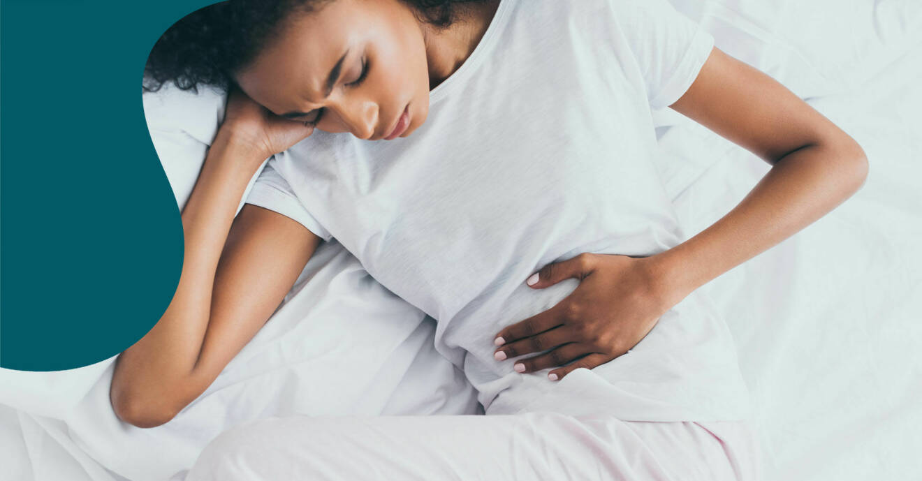 En kvinna ligger i sängen med svåra magsmärtor.