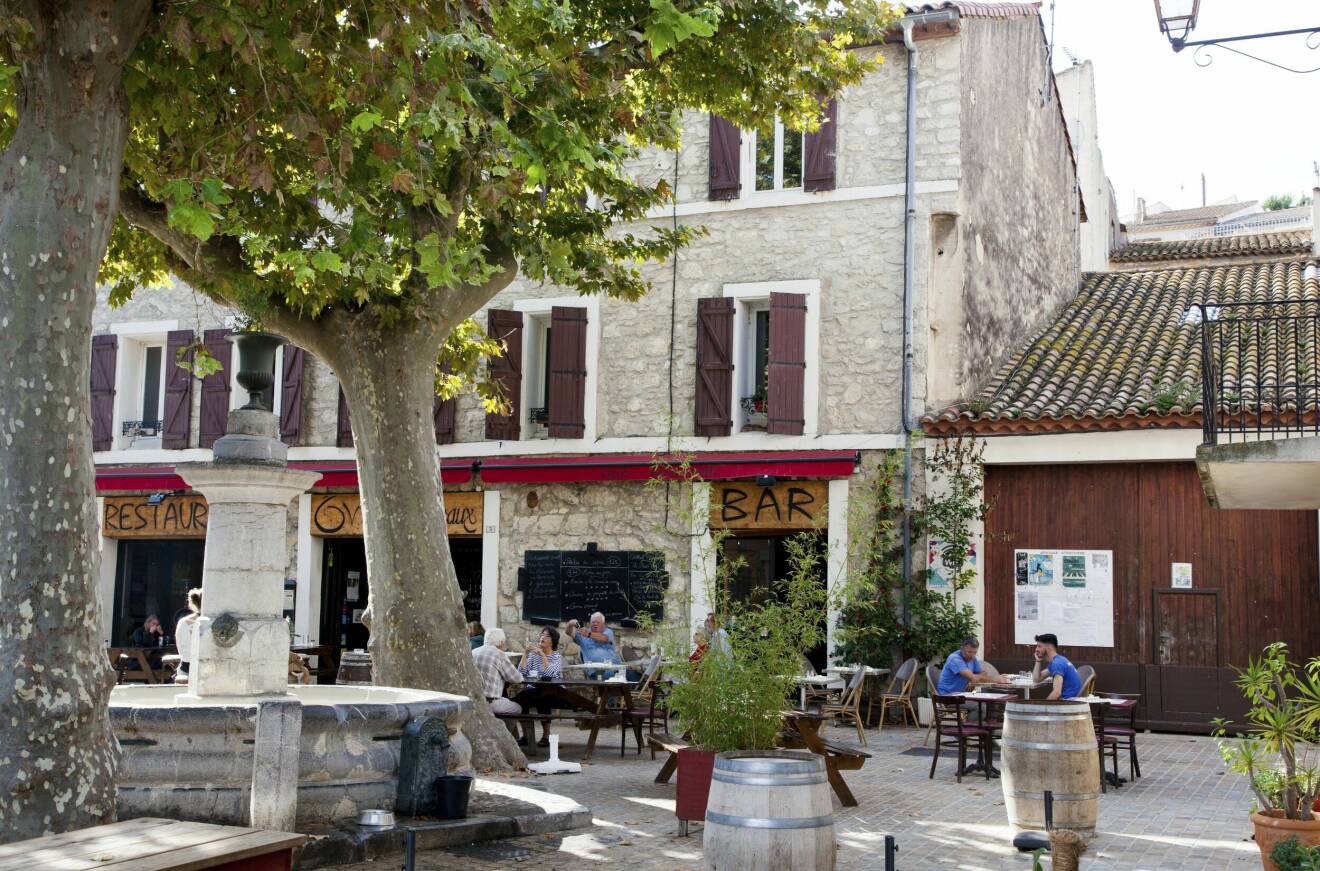På ett kafé vid ett torg i byn Peyriac-de-Mer i Frankrike sitter människor och fikar.