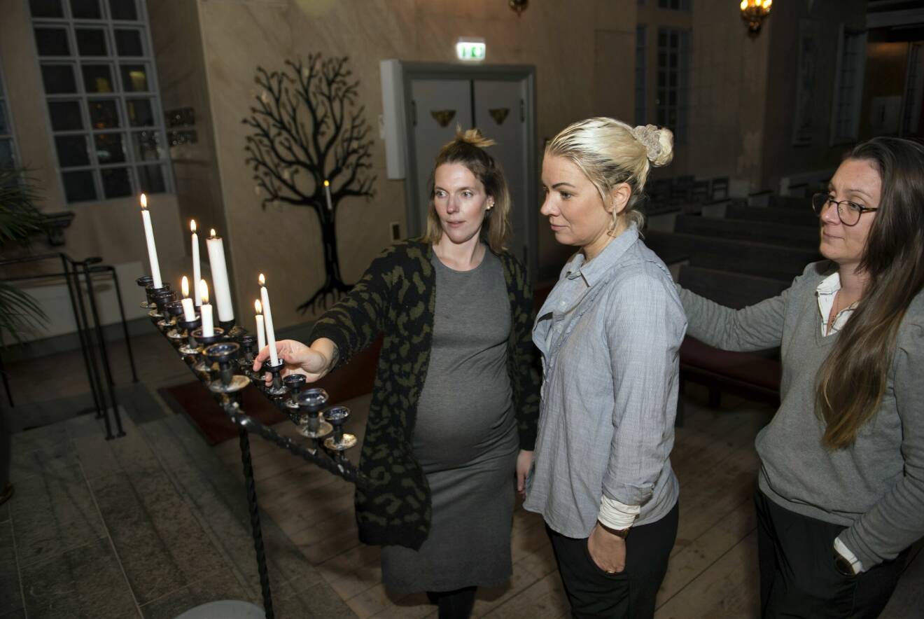 Tre kvinnor som mist sina barn tänder ljus tillsammans i en kyrka.
