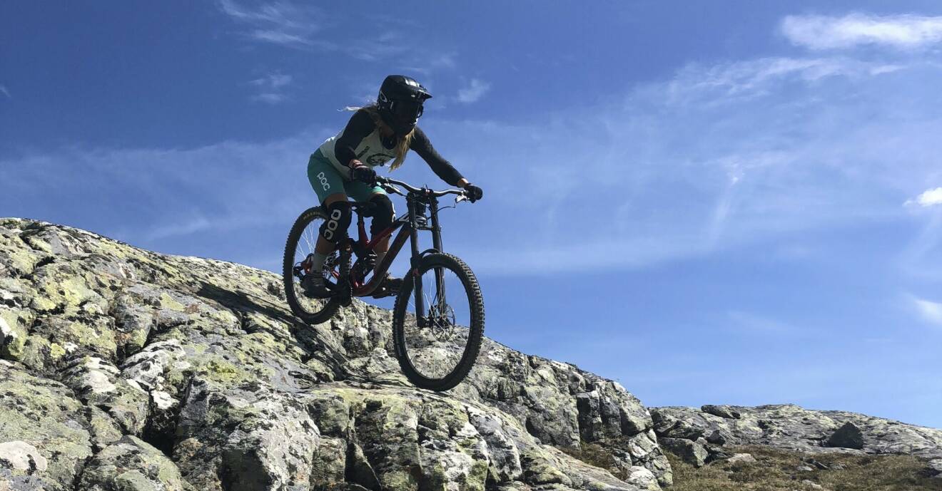 En ung kvinna cyklar mountainbike nerför ett berg.