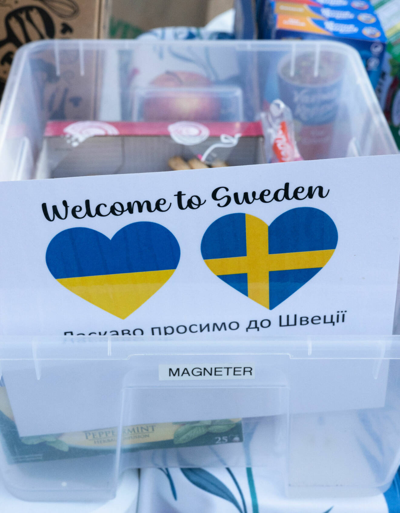 En skylt med den svenska och ukrainska flaggan i varsitt hjärta och texten ”welcome to Sweden" i en låda med småkakor utanför Migrationsverket i Malmö.