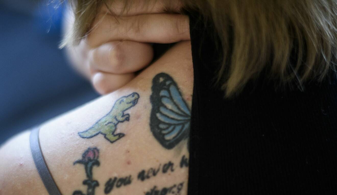 Malin Magnussen visar den lilla dinosaurien som hon låtit tatuera på överarmen.