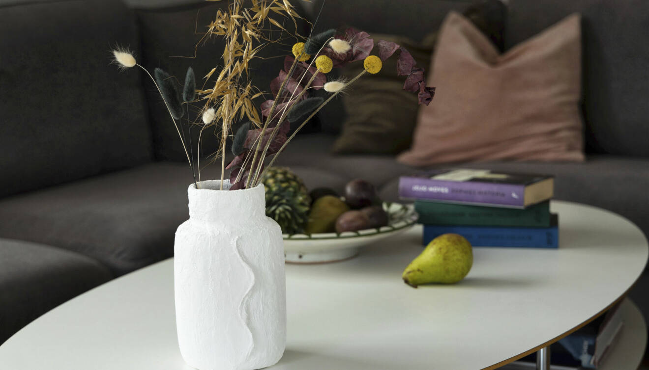 En vas på ett soffbord med en soffa med kuddar i bakgrunden.