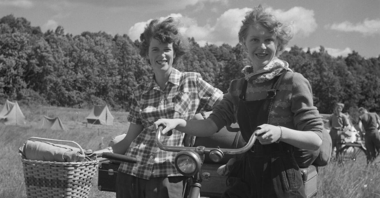 Två tjejer 1951 med cyklar och tält i bakgrunden.