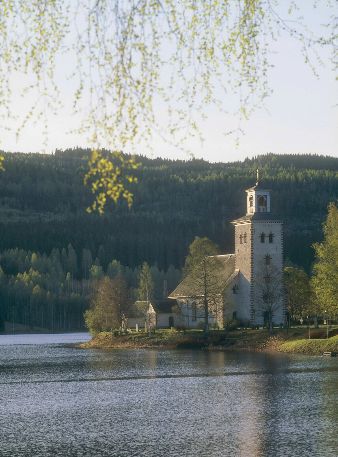 Vacker kyrka i Gräsmark i Värmland omgiven av vatten.