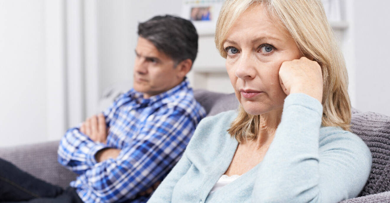 Ett par i 50-årsåldern sitter i varsin ände av tv-soffan och ser ut att vara långt ifrån varandra.