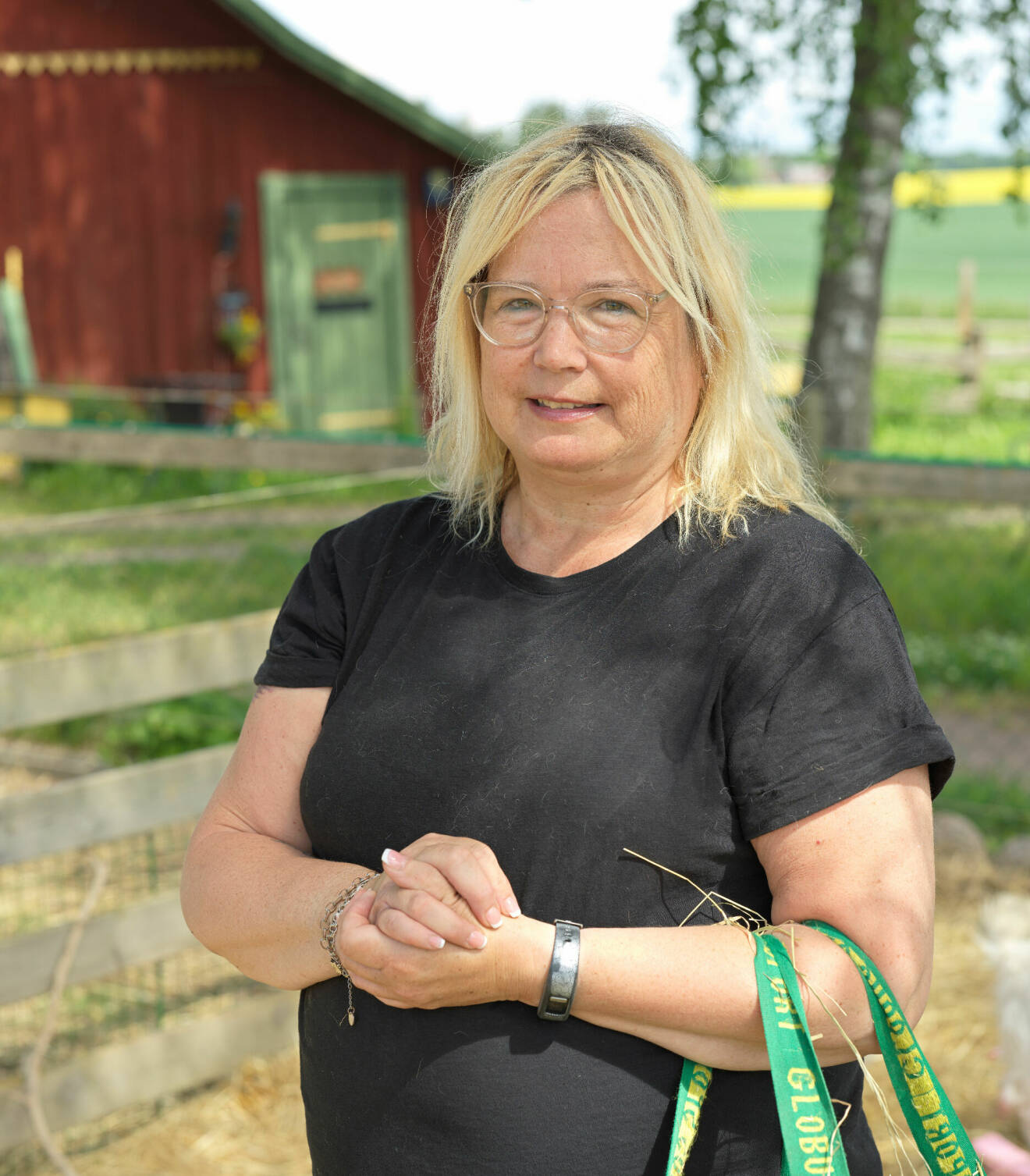 Anneli Magnusson står i en hage och runt ena armen hänger en kasse med hö.