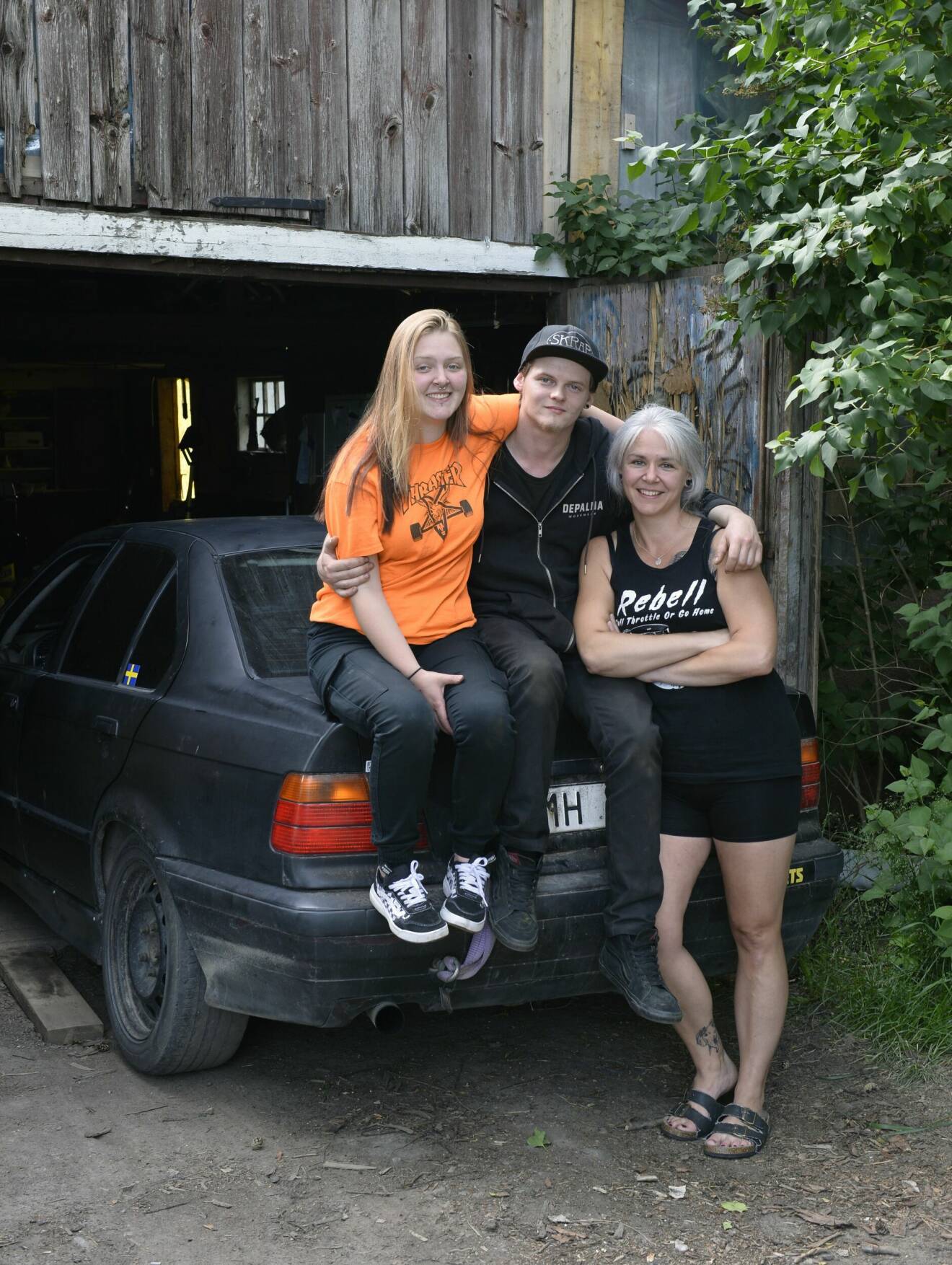Victor Rydén, Michelle Smedman Frid, Liselott Smedman sitter på en bil och håller om varandra.