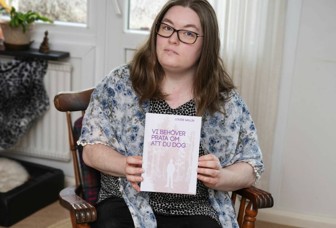 Louise sitter på en stol och håller sin bok ”Vi behöver prata om att du dog” framför sig.