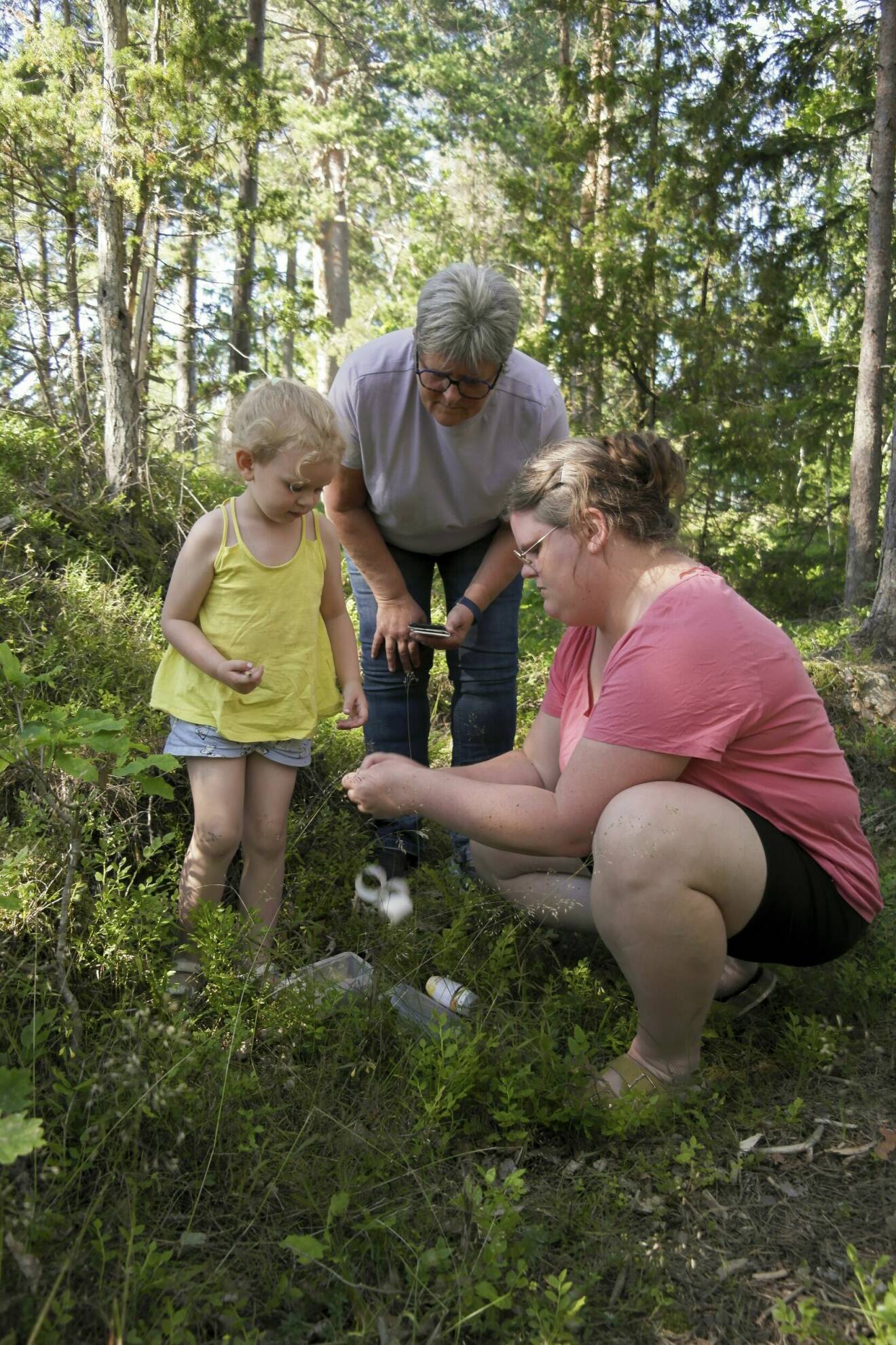 Marinette Olsson, dottern Sarah Brandin och barnbarnet Idun undersöker en funnen geocache.