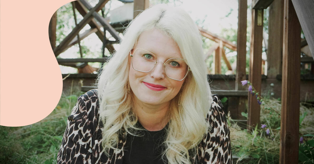Ida Högström, som driver Medberoendepodden, fotograferad utomhus med träställningar i bakgrunden. Ida har blont lockigt hår och klädd i en leopardmönstrad kavaj.