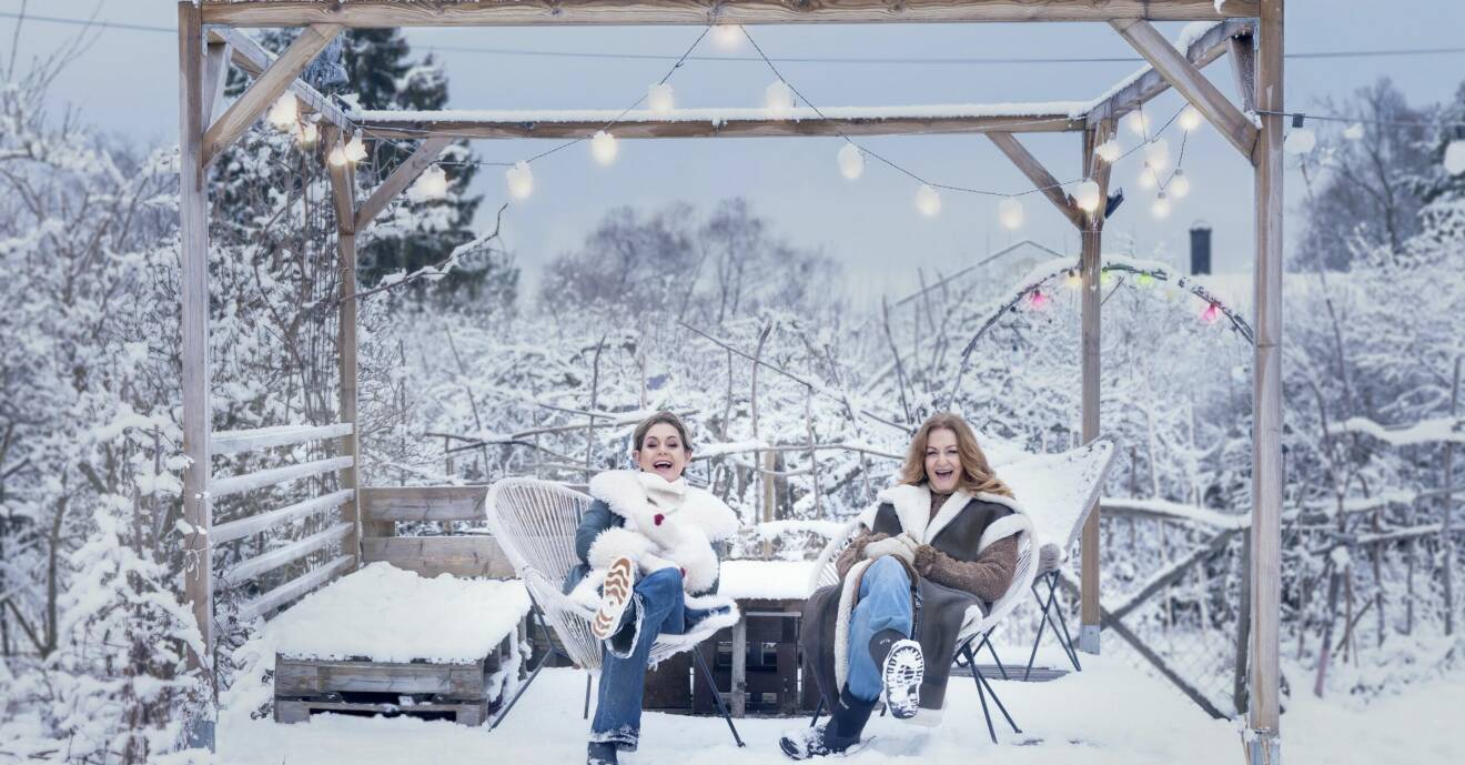 Sångerskorna Helen Sjöholm och Anna Stadling sitter i en pergola, täckt av snö och ljuskäglor.