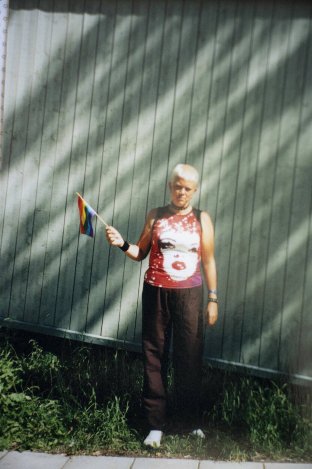 En ung Suzann Larsdotter med snaggat, ljust hår och Pride-flagga i handen.