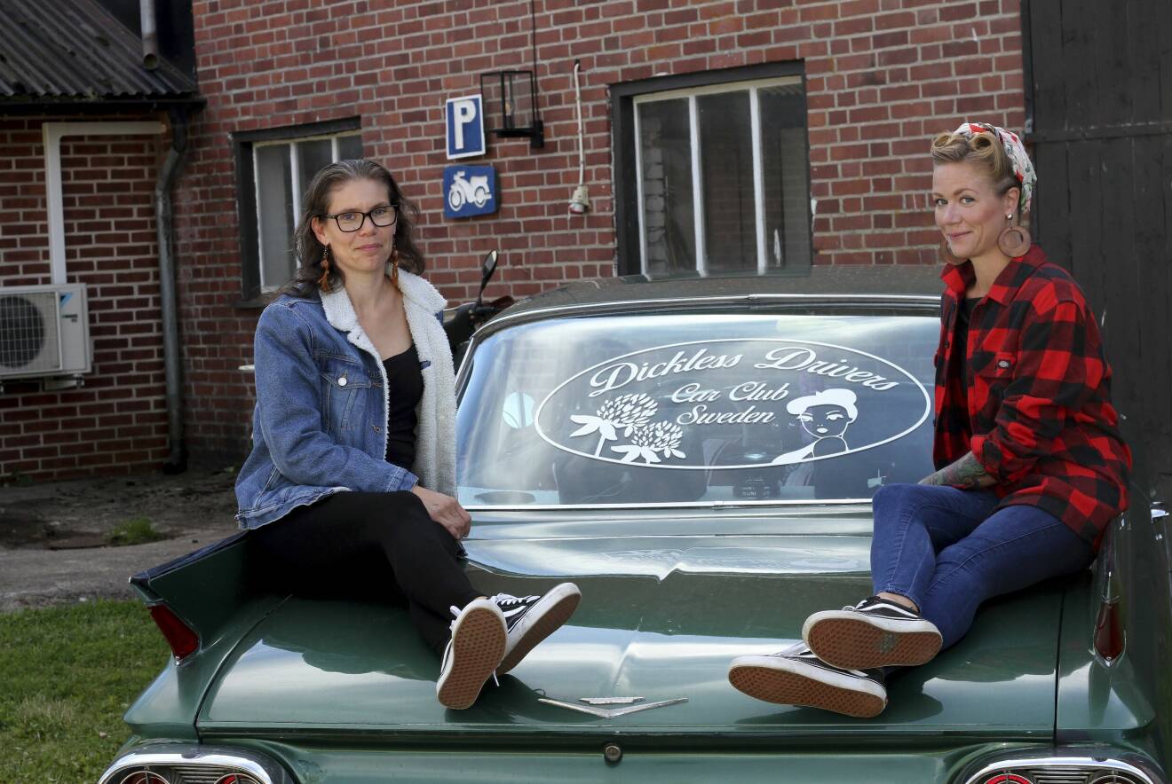 Annelie Sundberg och Julia Lind sitter uppkrupna på veteranbilen med Dickless Drivers emblem på bakrutan mellan sig.