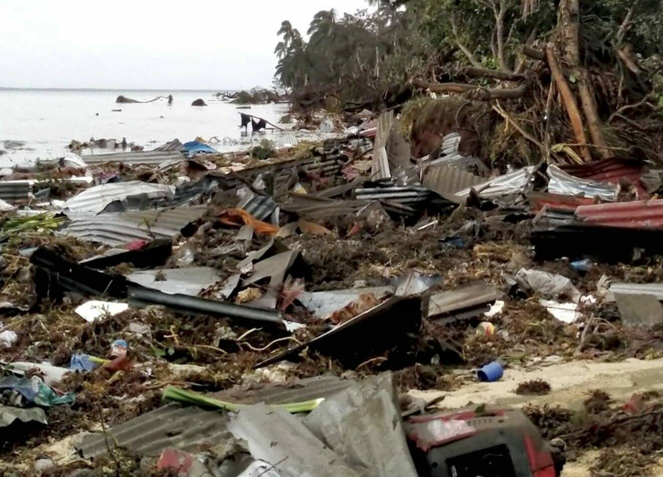 Massor av uppspolad bråte på land efter vulkanutbrott och tsunami.