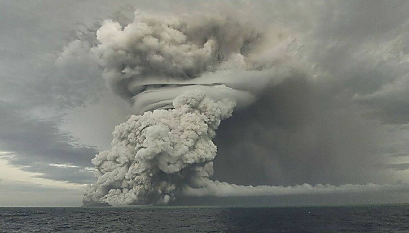 Ett tort svampmoln stiger upp i luften från havet i samband med undervattenvulkanens utbrott utanför Tonga.