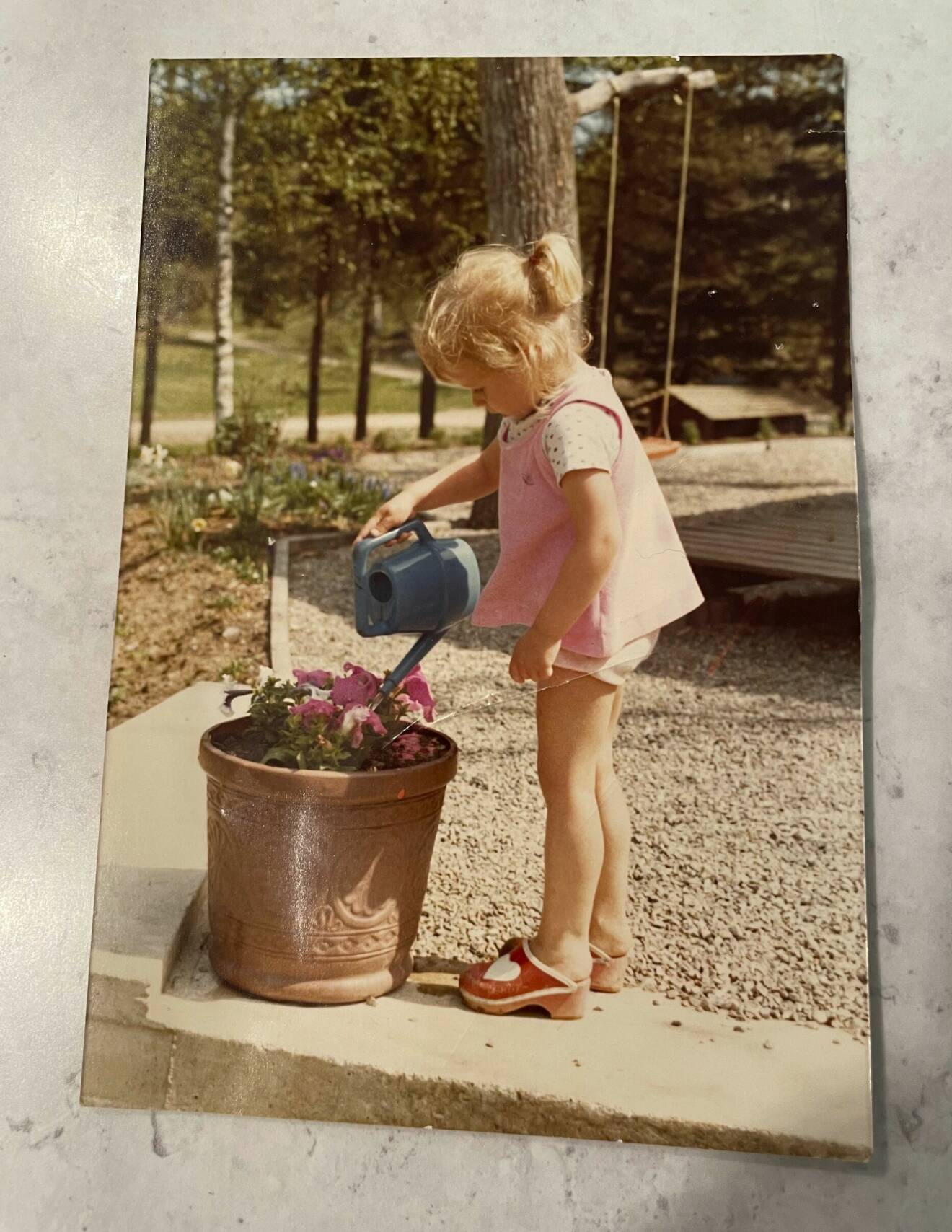 Barnboksförfattaren Cecilia Rojek som liten flicka, står och vattnar blommor.