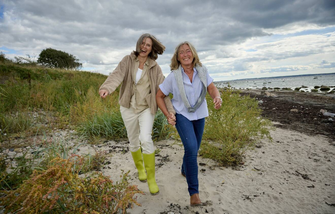 Birgitta Hågemark Olshov håller och Annika Erlandsson Olshov skrattar där de går hand i hand på stranden i Viken vid Öresund.