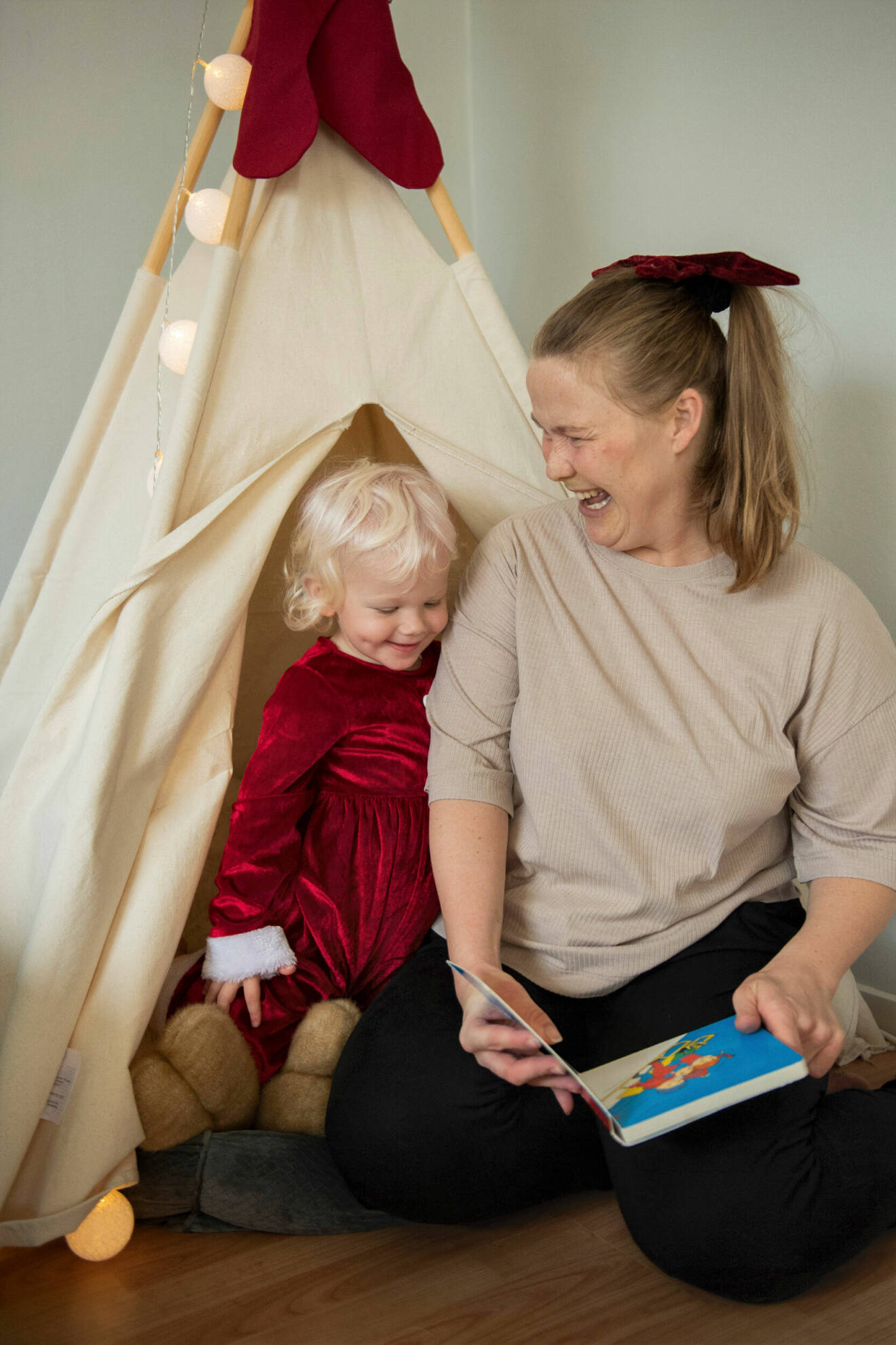 Jenny Larsson, mamma med cp-skada, läser tillsammans med dottern Astrid framför ett tält i vardagsrummet.