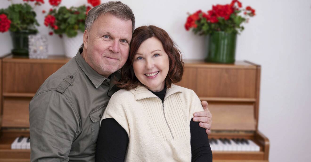 Porträttbild på Marie och Richard. I bakgrunden syns ett piano och en röd julblomma. De ler och Richard håller om Marie.